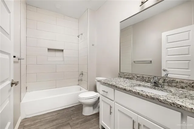 a bathroom with a granite countertop toilet a sink and a bathtub