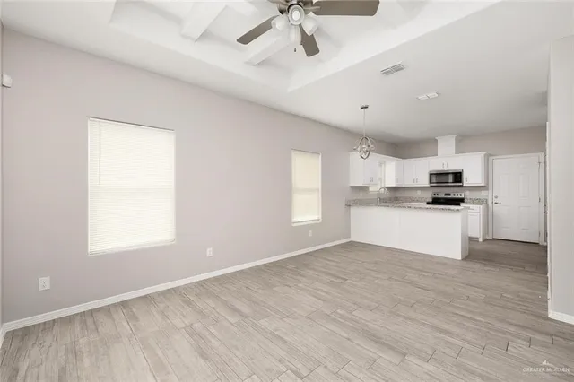 an empty room with wooden floor cabinet and windows