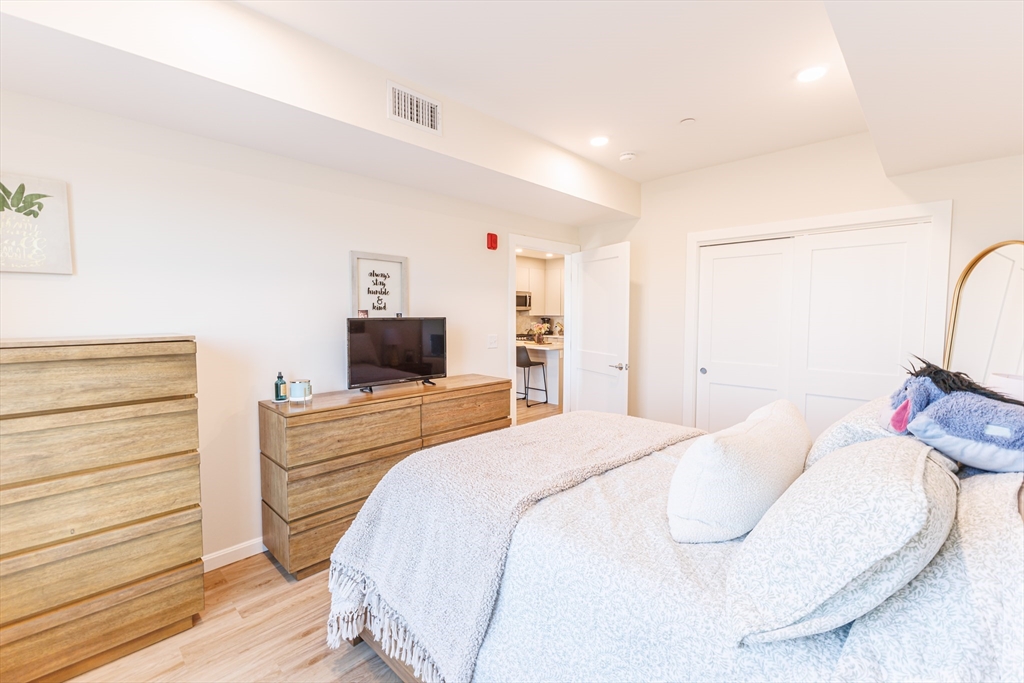 458 Washington Street, Unit 304 Boston, MA 02135 - Photo 7 of 13 a bedroom with a bed and a flat screen tv