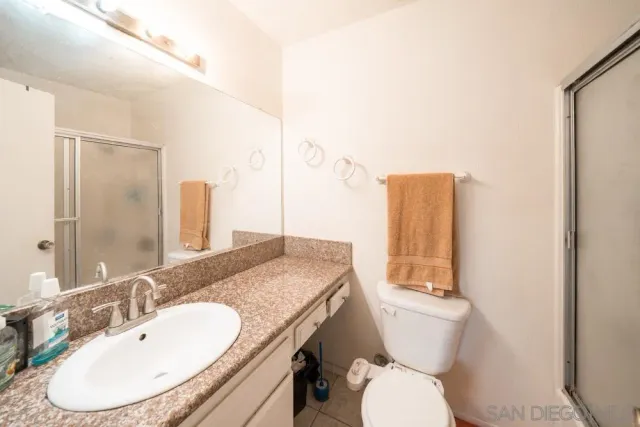 a bathroom with a granite countertop toilet sink and mirror