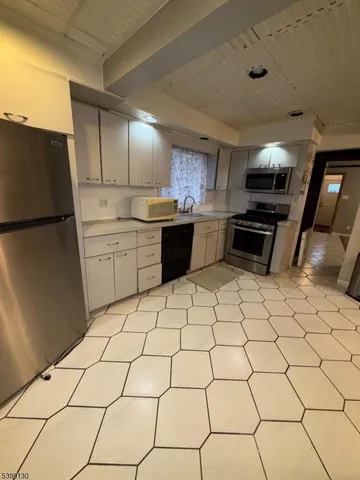 a kitchen with stainless steel appliances kitchen island granite countertop a sink and a refrigerator