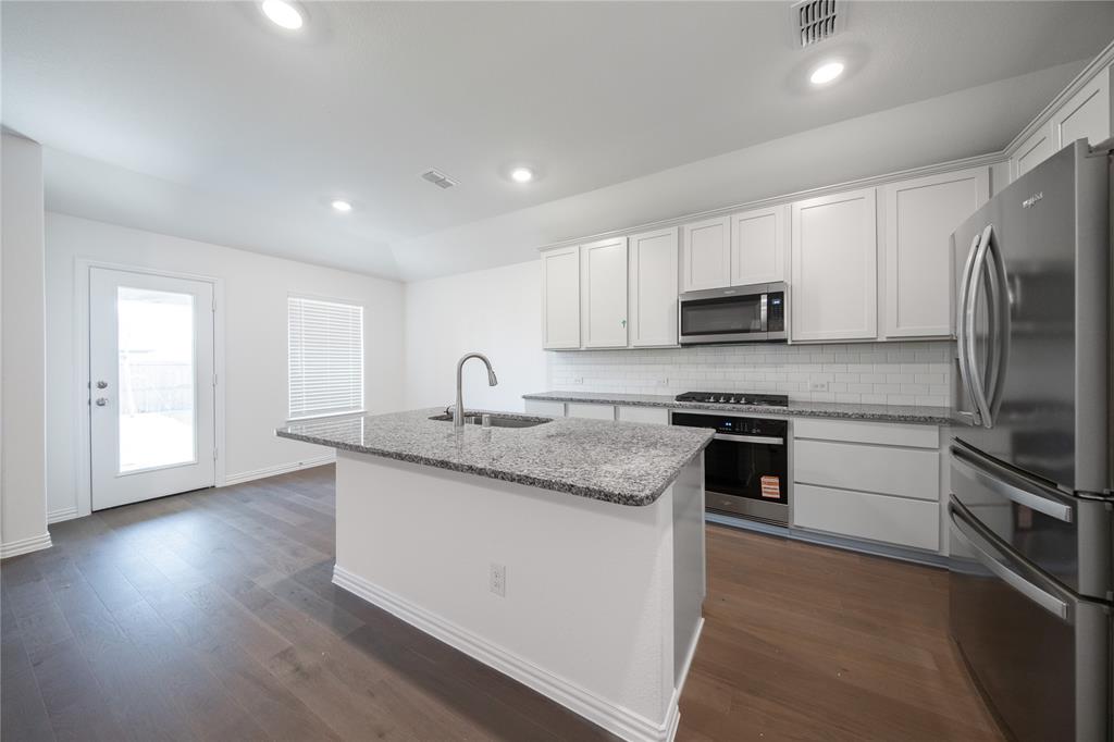 2015 Partridge Road Princeton, TX 75407 - Photo 4 of 27 a kitchen with stainless steel appliances granite countertop a sink stove microwave and refrigerator
