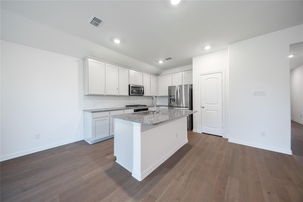 2015 Partridge Road Princeton, TX 75407 - Photo 5 of 27 a kitchen with stainless steel appliances granite countertop a white stove top oven and white cabinets