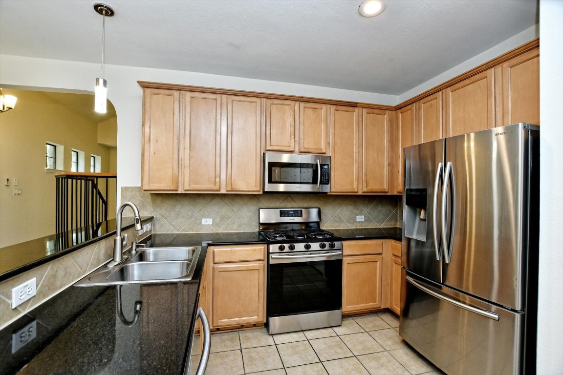 1310 West Parmer Lane, Unit 2803 Austin, TX 78727 - Photo 18 of 40 a kitchen with stainless steel appliances granite countertop a refrigerator stove and sink