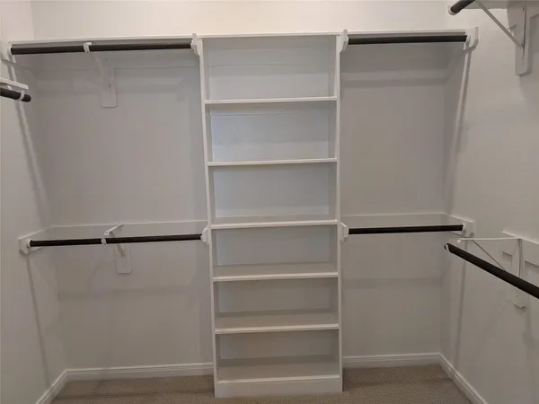 a view of walk in closet with empty racks