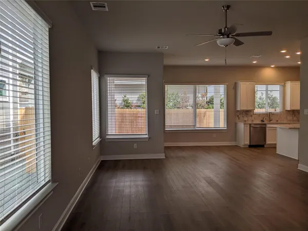 an empty room with wooden floor and windows