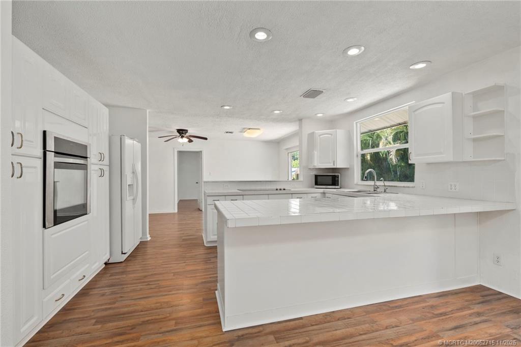 5801 Southeast Cable Drive Stuart, FL 34997 - Photo 14 of 48 a large kitchen with stainless steel appliances granite countertop a large counter top a sink and a refrigerator