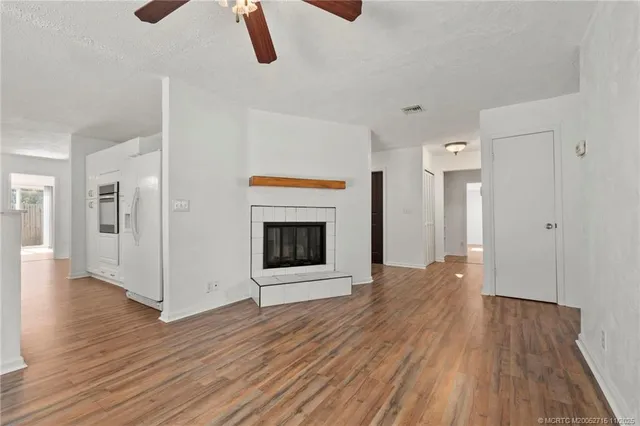 a view of an empty room with wooden floor and a fireplace