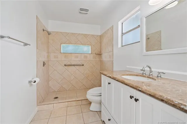 a backyard of a house with table and chairs plants and large tree