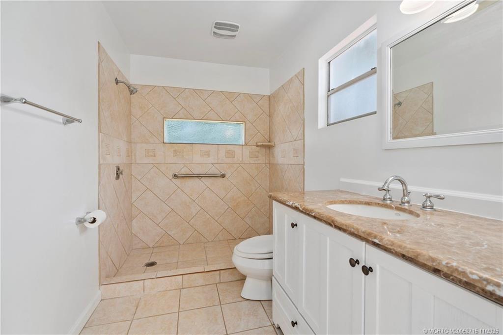 5801 Southeast Cable Drive Stuart, FL 34997 - Photo 34 of 48 a bathroom with a granite countertop sink a toilet and a mirror