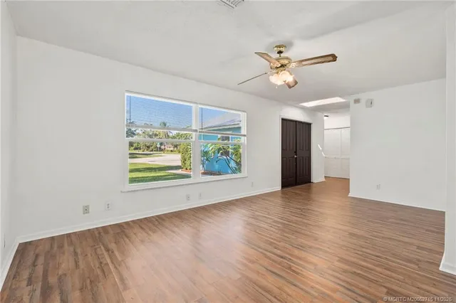 an empty room with wooden floor a ceiling fan and windows