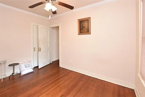 an empty room with wooden floor chandelier fan and windows