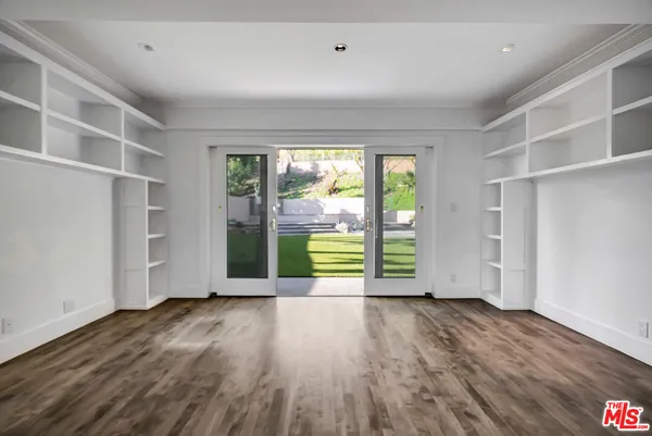 a view of an empty room with wooden floor fireplace and a window