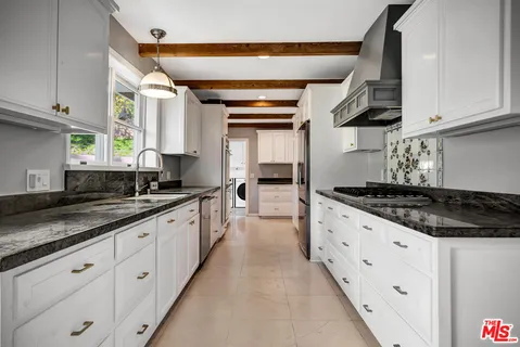 a kitchen with granite countertop white cabinets and stainless steel appliances