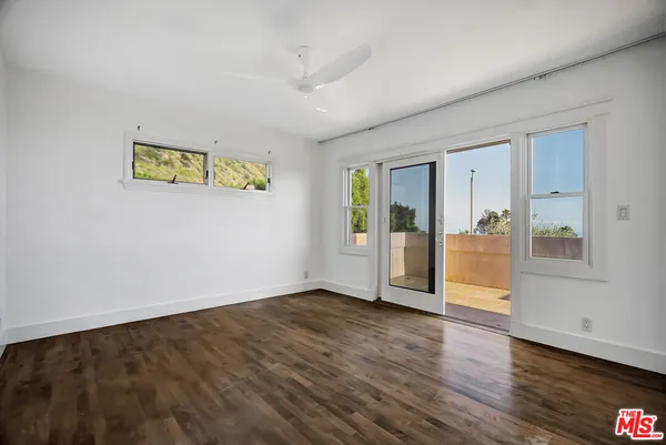 an empty room with windows and ceiling fan