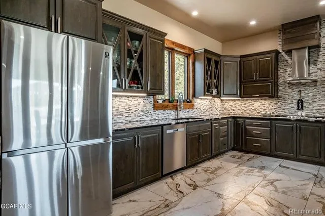 a kitchen with stainless steel appliances granite countertop a refrigerator and a sink