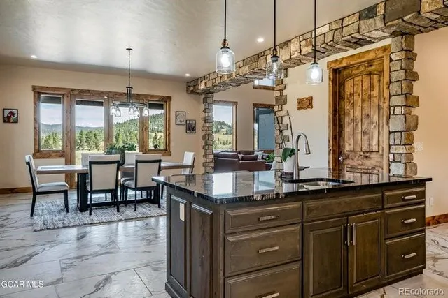 a kitchen with kitchen island granite countertop a table chairs sink and cabinets