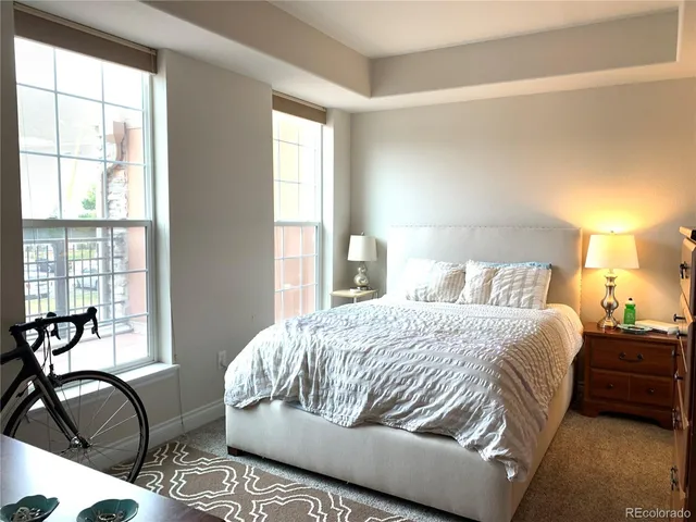 a bedroom with a bed chair and three windows