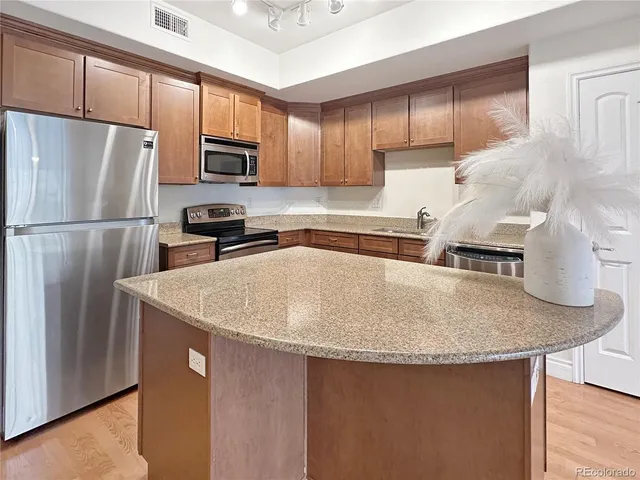 a kitchen with stainless steel appliances granite countertop a sink a stove a refrigerator a washer and dryer