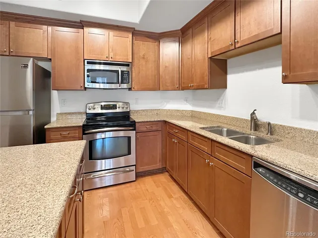 a kitchen with granite countertop a sink stove and refrigerator