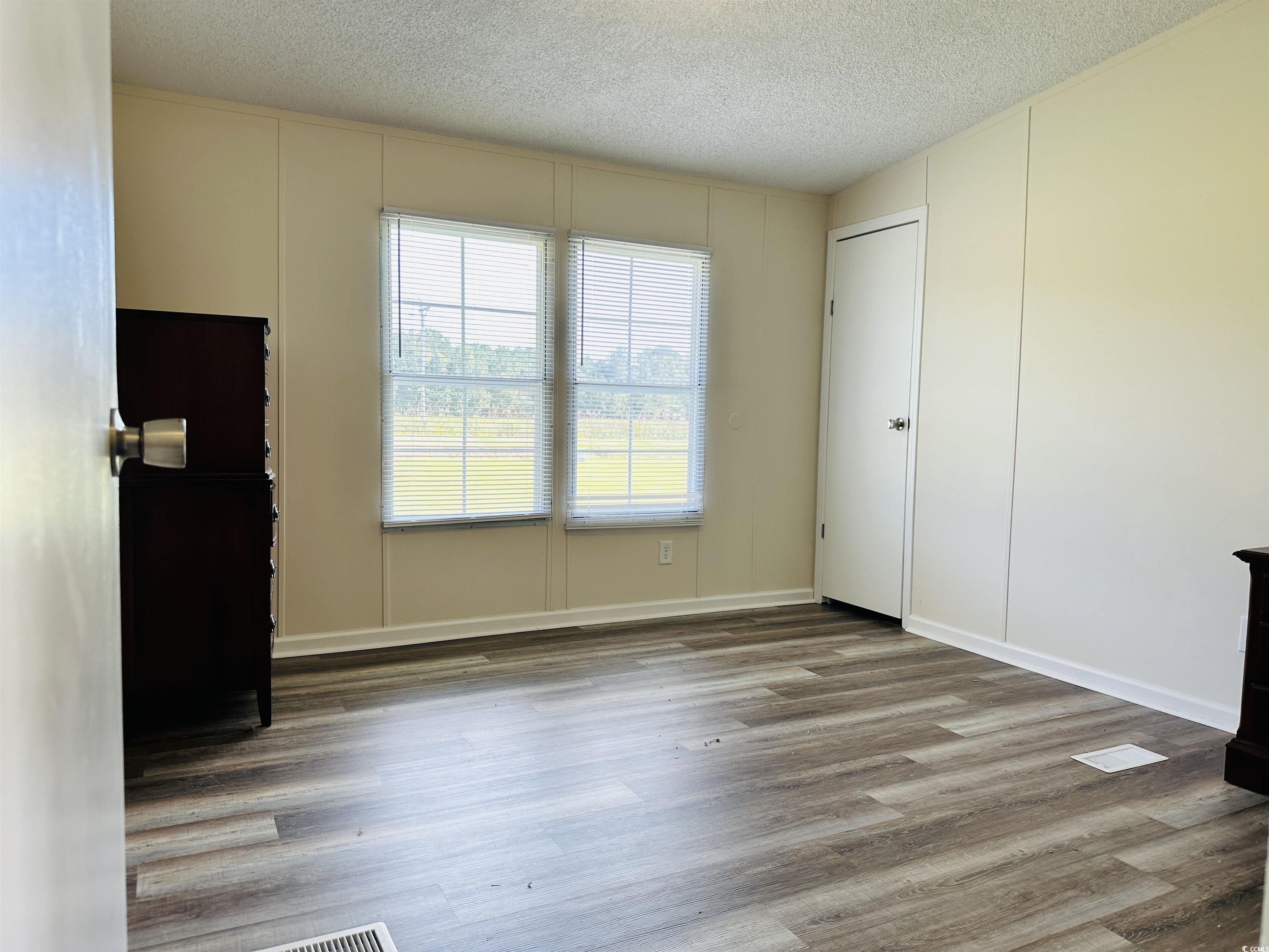 2067 Willow Creek Road Effingham, SC 29541 - Photo 14 of 40 Unfurnished living room featuring a textured ceiling, wood finished floors, and a decorative wall