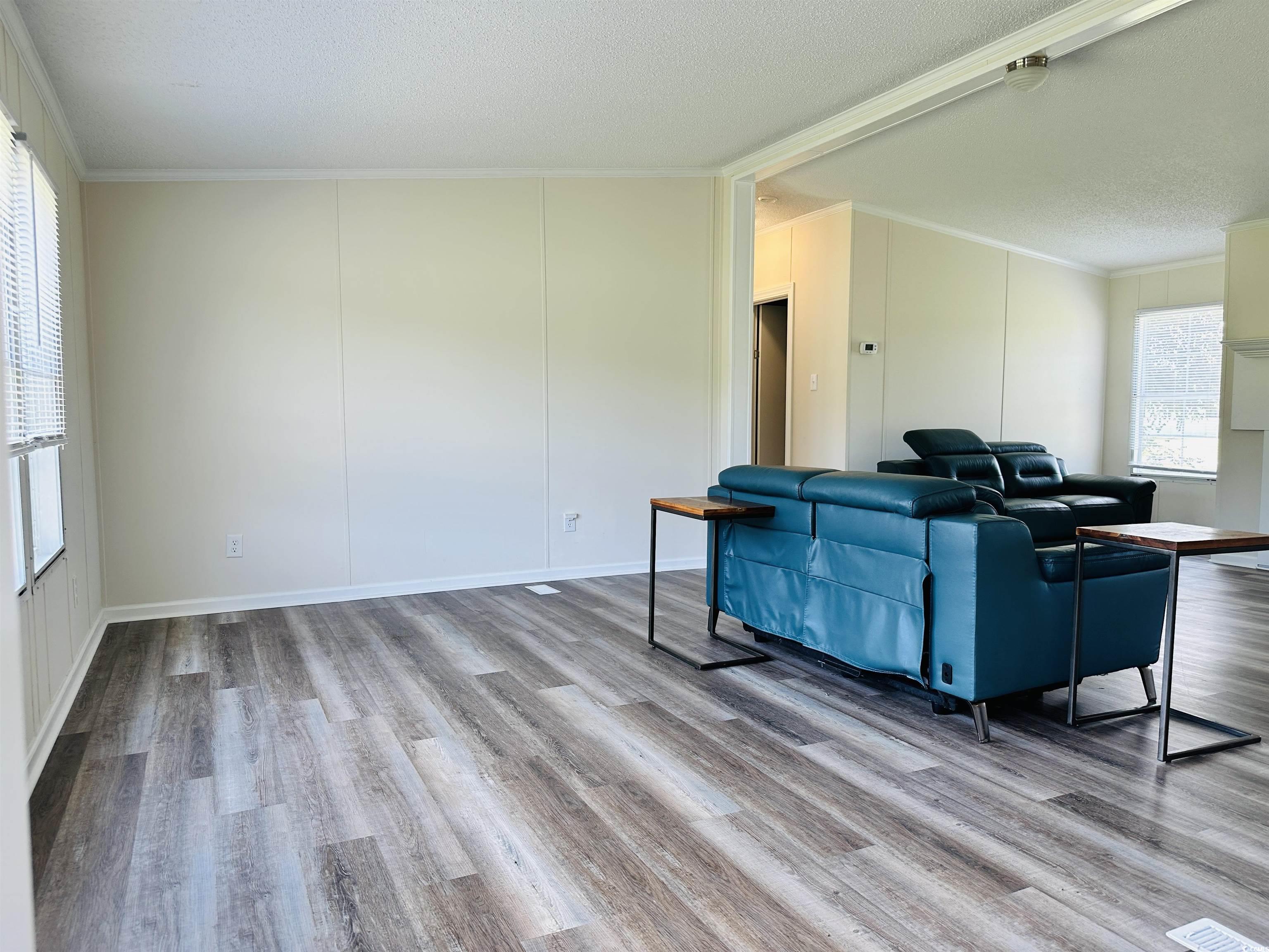 2067 Willow Creek Road Effingham, SC 29541 - Photo 20 of 40 Living room featuring ornamental molding, light wood-type flooring, and a textured ceiling