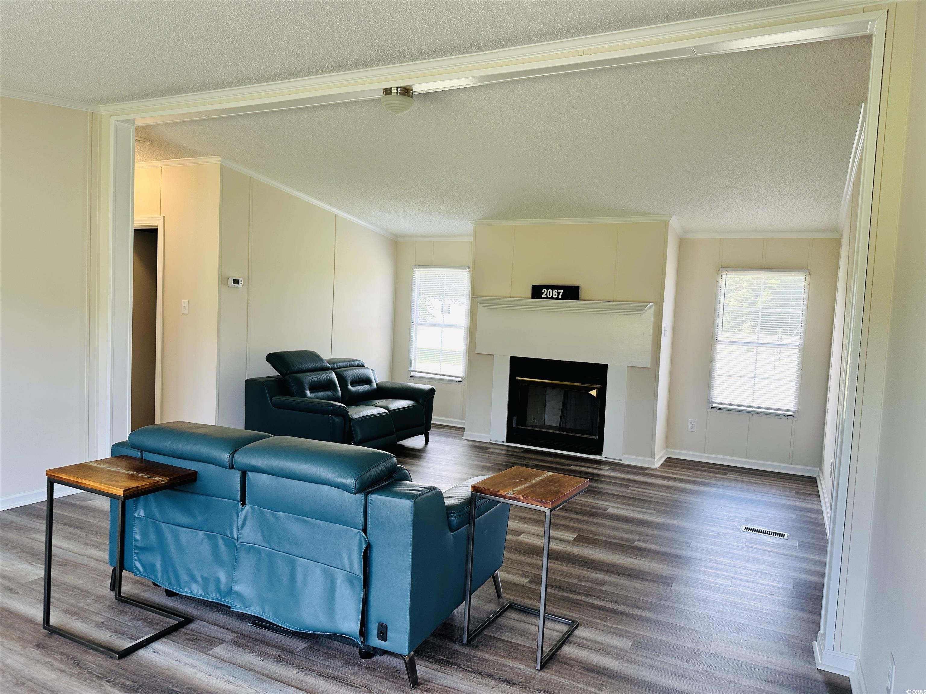2067 Willow Creek Road Effingham, SC 29541 - Photo 22 of 40 Living room featuring crown molding, a glass covered fireplace, wood finished floors, and a textured ceiling