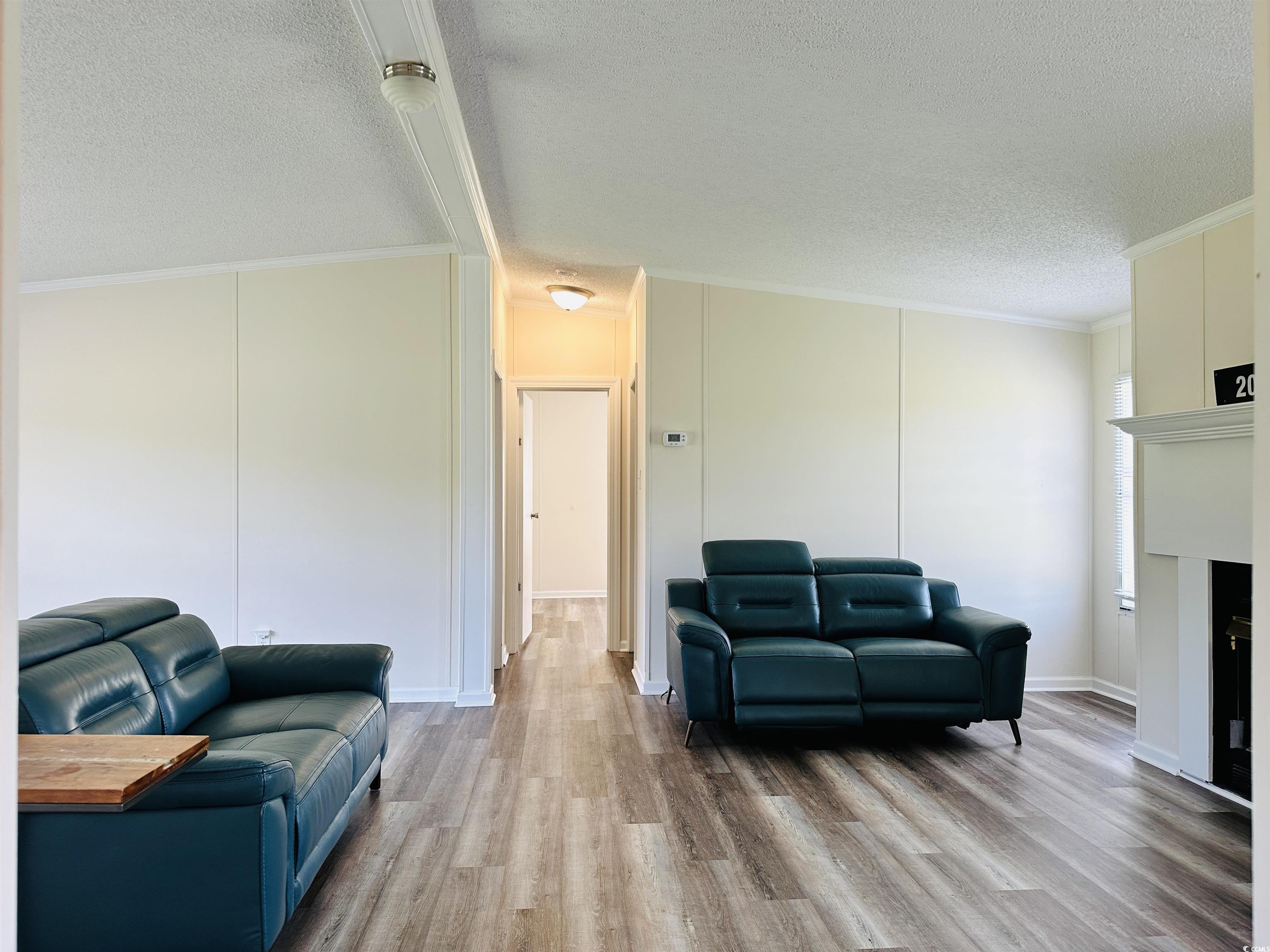 2067 Willow Creek Road Effingham, SC 29541 - Photo 25 of 40 Living room with crown molding, light wood-style floors, and a textured ceiling