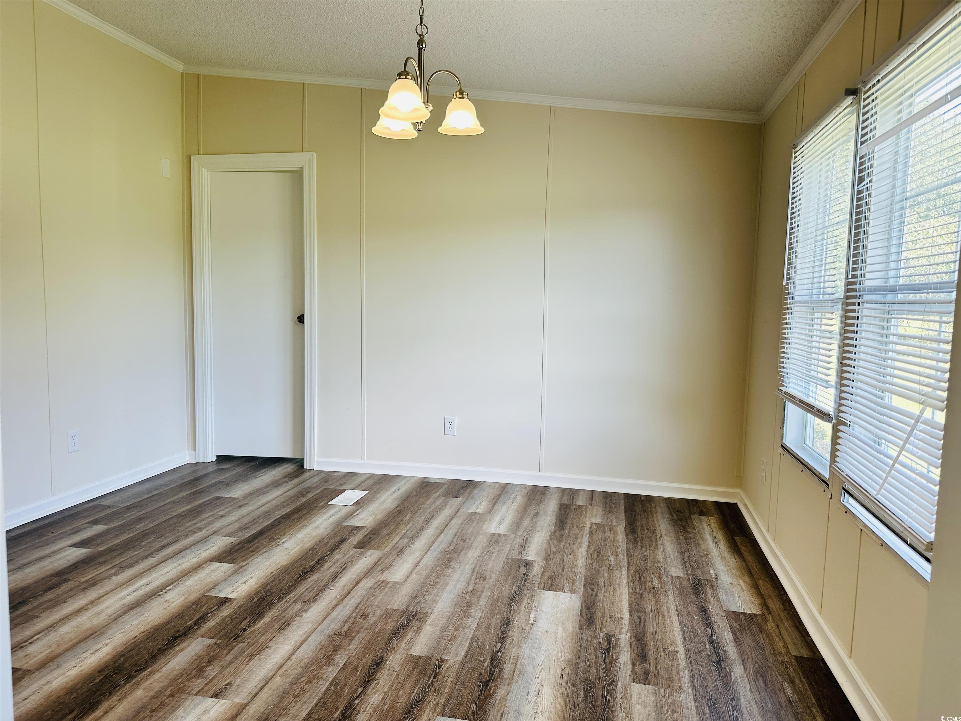 2067 Willow Creek Road Effingham, SC 29541 - Photo 29 of 40 Unfurnished dining area featuring healthy amount of natural light, ornamental molding, wood finished floors, a chandelier, and a textured ceiling