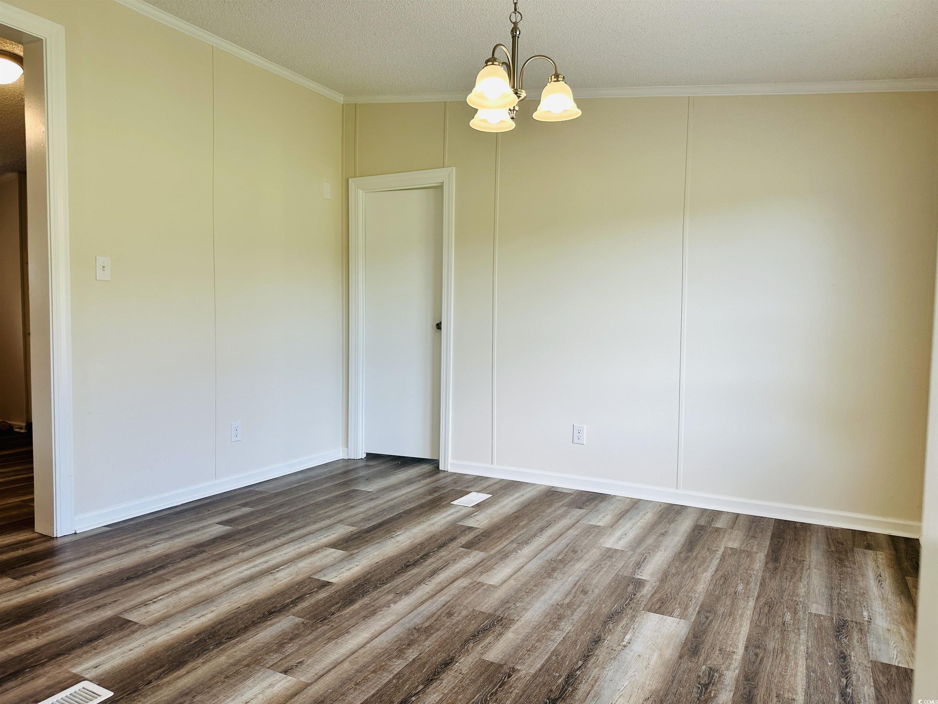 2067 Willow Creek Road Effingham, SC 29541 - Photo 30 of 40 Unfurnished dining area with crown molding, wood finished floors, a chandelier, and a textured ceiling