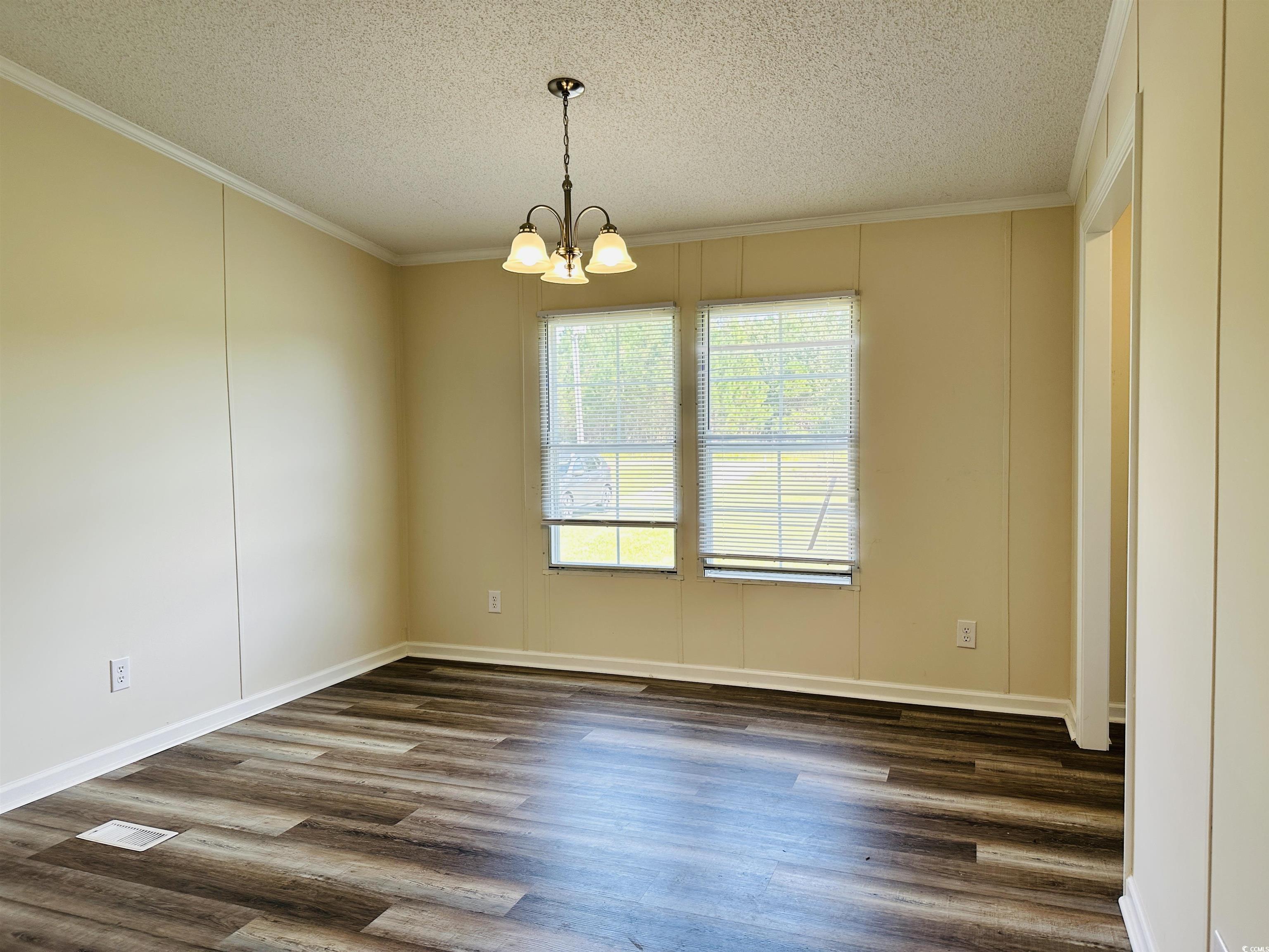 2067 Willow Creek Road Effingham, SC 29541 - Photo 31 of 40 Unfurnished dining area with ornamental molding, dark wood-type flooring, a textured ceiling, and a chandelier