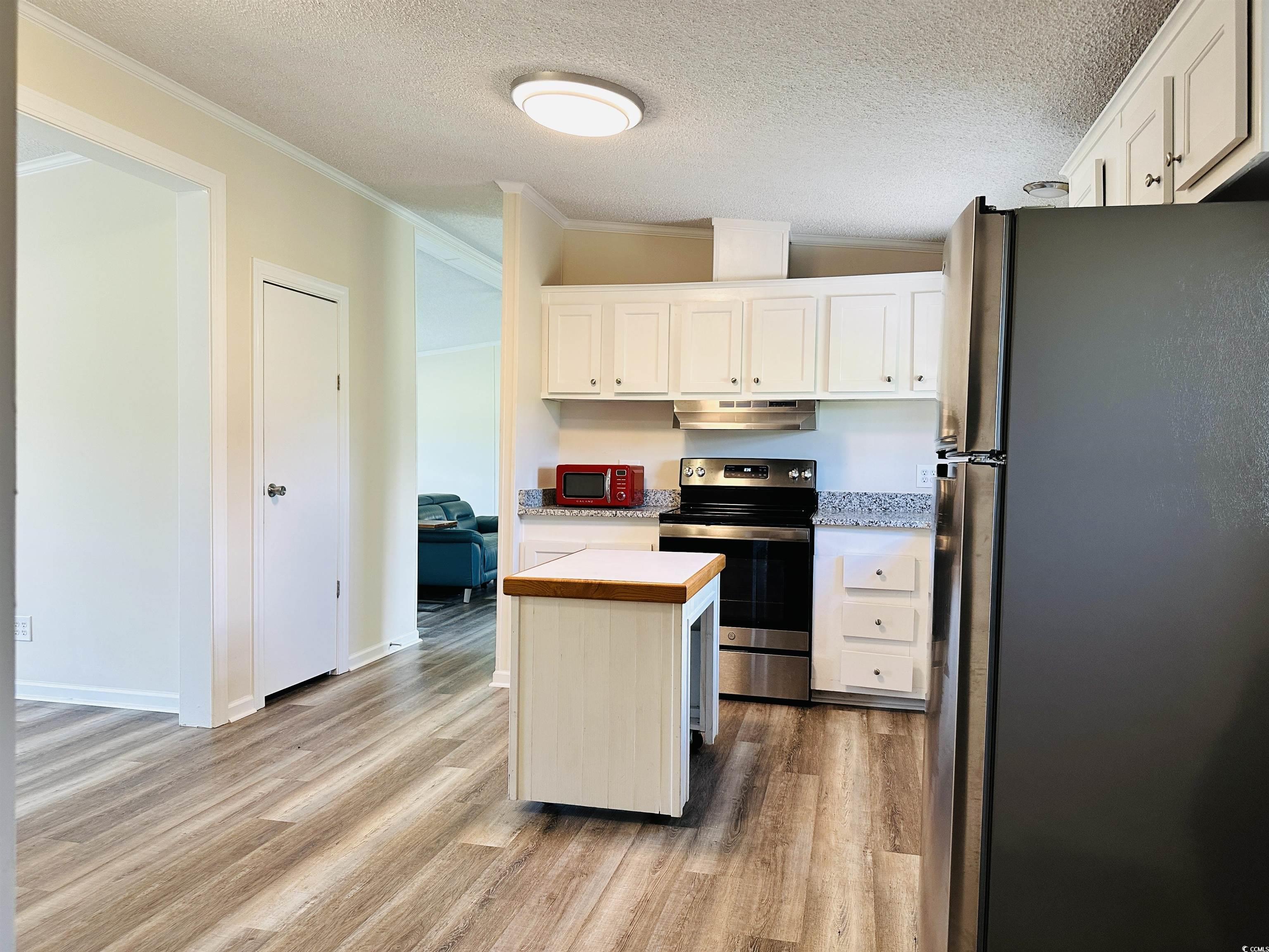 2067 Willow Creek Road Effingham, SC 29541 - Photo 32 of 40 Kitchen with light countertops, appliances with stainless steel finishes, light wood-style flooring, a textured ceiling, and white cabinetry