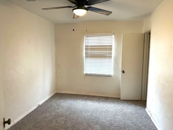 an empty room with a window and a ceiling fan