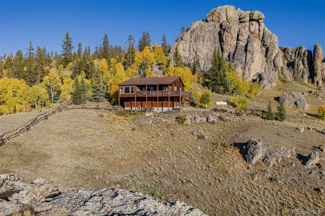 a view of a house with a yard and lawn chairs under an umbrella