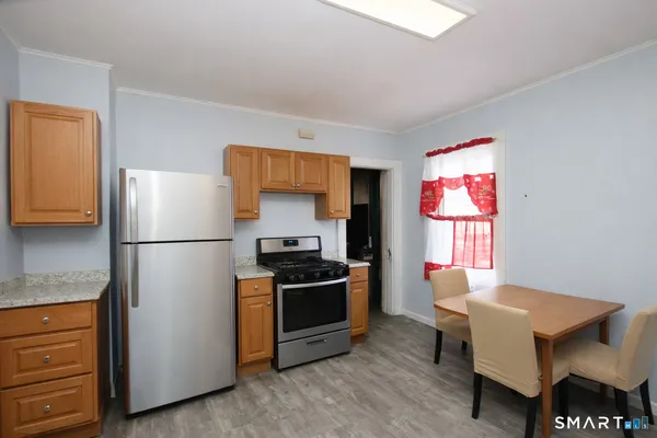 a kitchen with stainless steel appliances granite countertop a refrigerator a stove a sink and a dining table with wooden floor