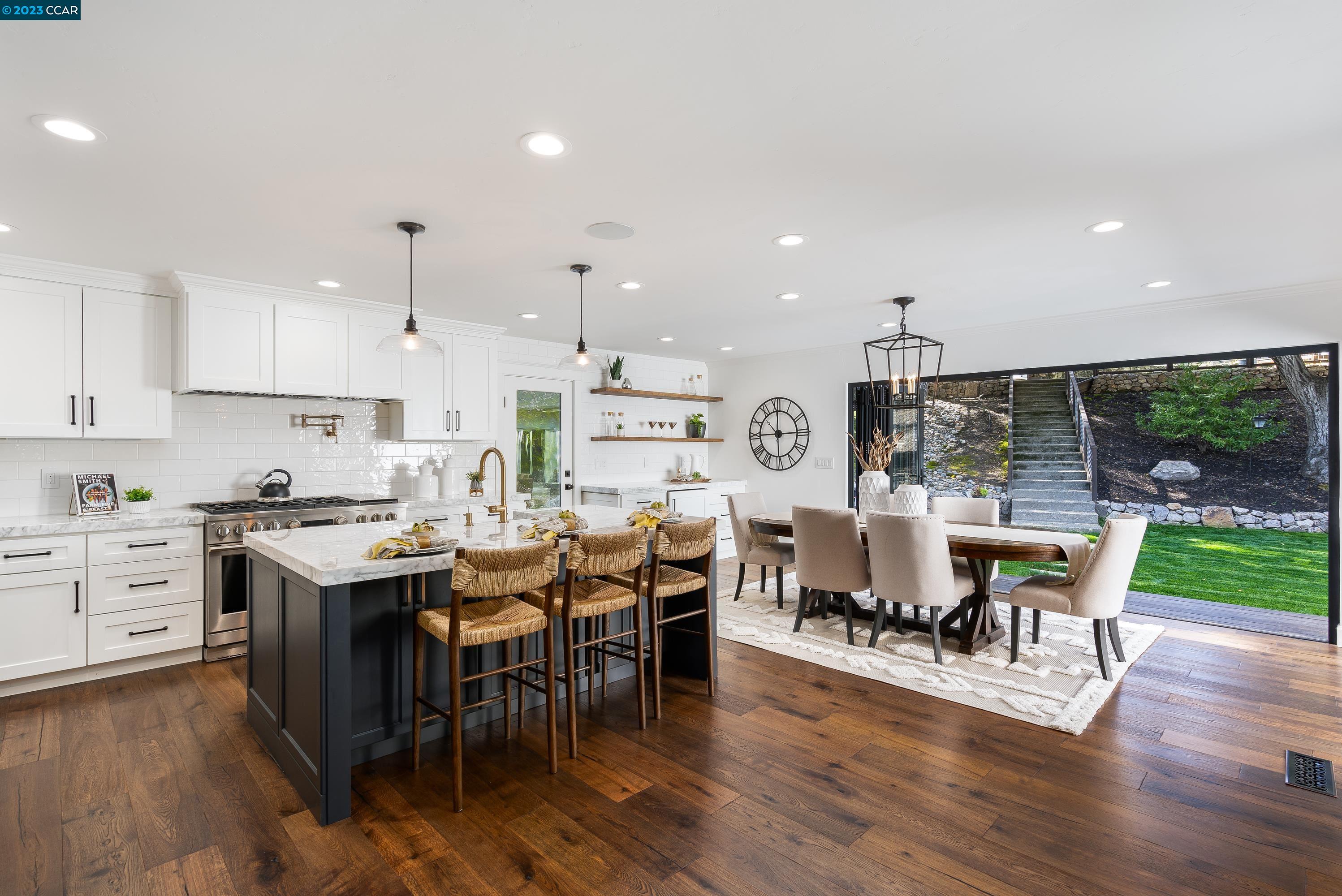 a view of a dining room and livingroom with furniture wooden floor a rug a fireplace and a chandelier