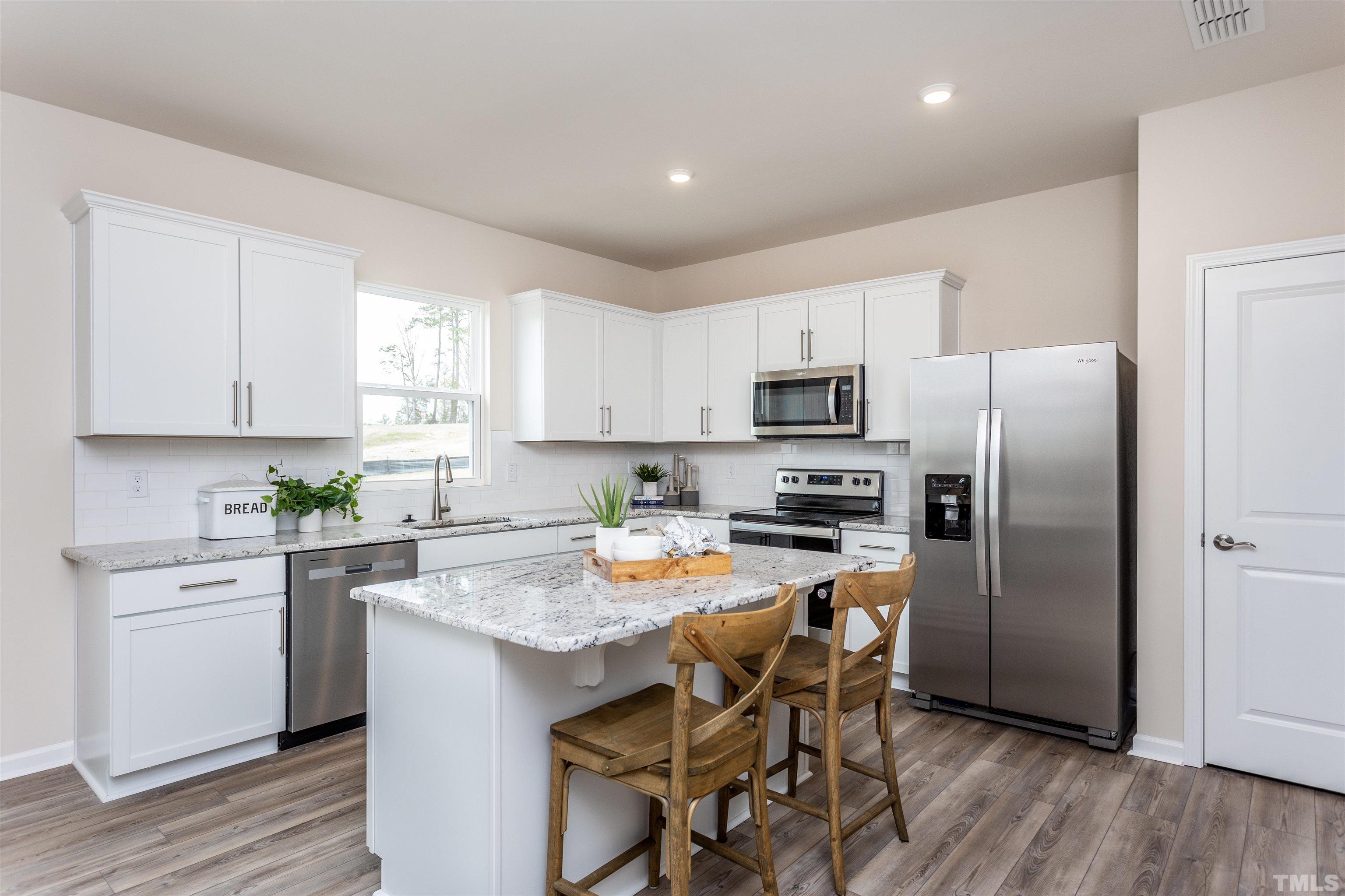 3469 Dragonfly River Raleigh, NC 27604 - Photo 17 of 26 a kitchen with stainless steel appliances granite countertop a refrigerator a sink a stove a dining table and chairs with wooden floor