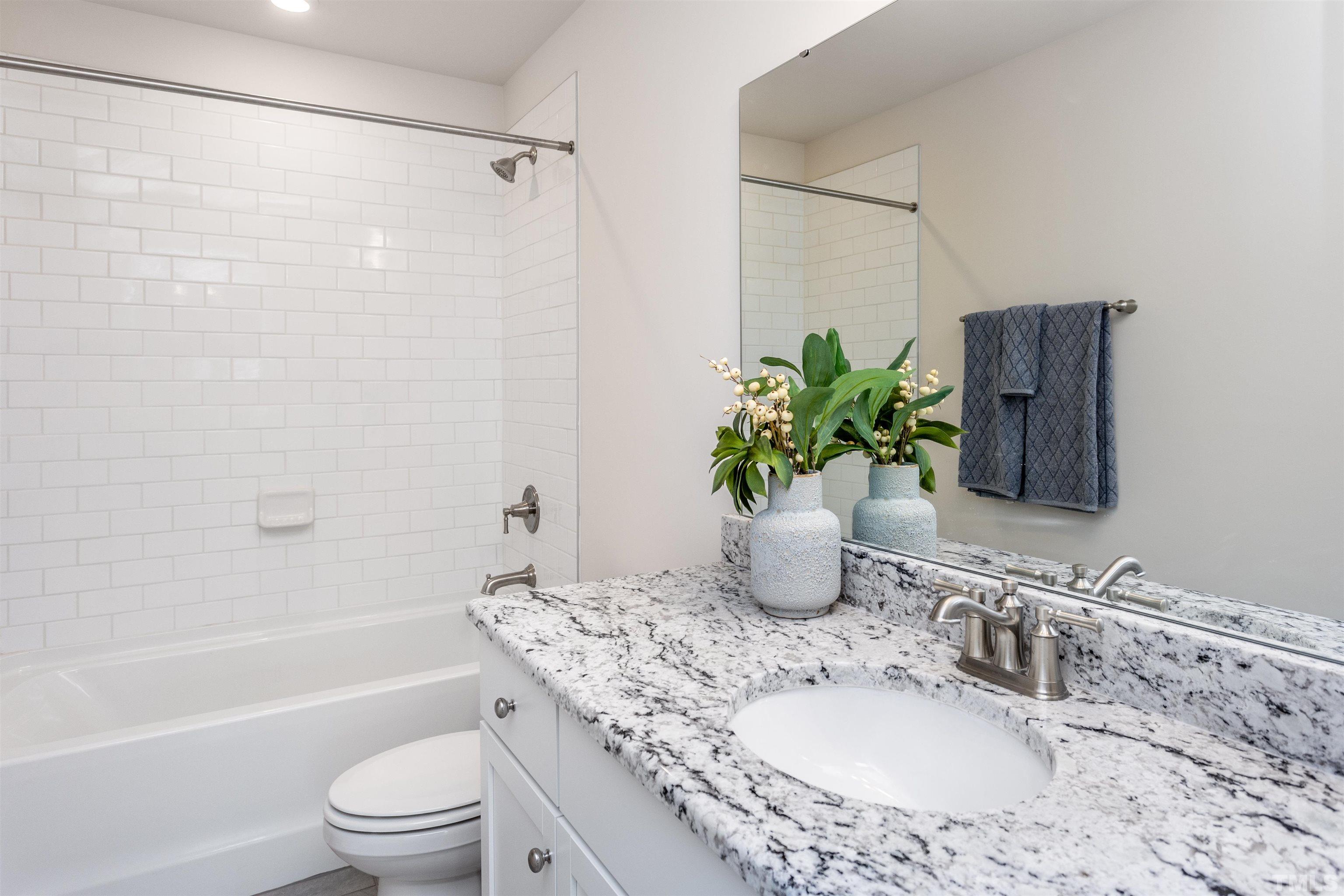 3469 Dragonfly River Raleigh, NC 27604 - Photo 26 of 26 a bathroom with a granite countertop sink a toilet a mirror a shower and vanity
