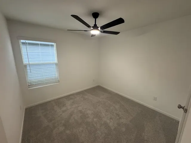 an empty room with ceiling fan and window
