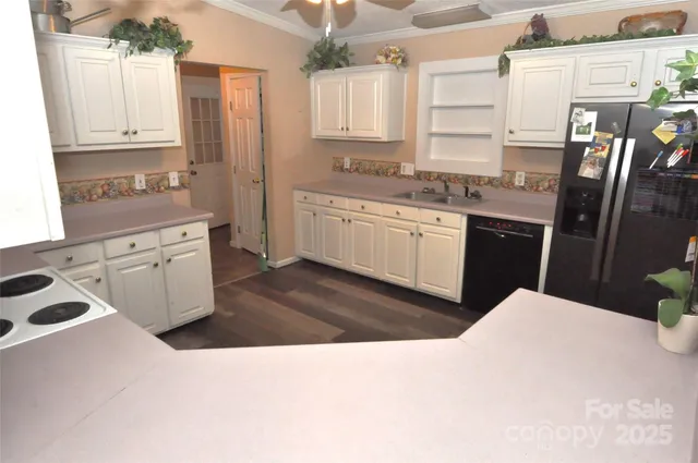 a kitchen with stainless steel appliances kitchen island granite countertop a sink refrigerator stove and white cabinets