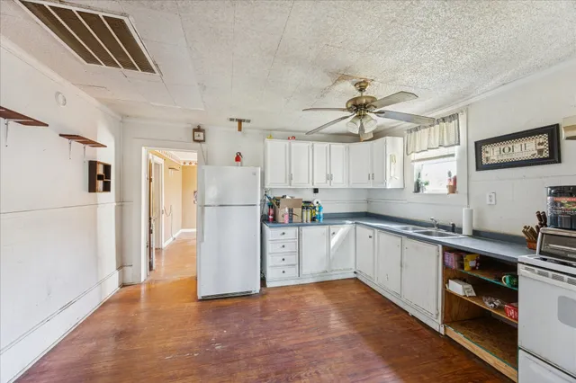 a kitchen with stainless steel appliances a refrigerator a sink dishwasher a stove and white cabinets with wooden floor