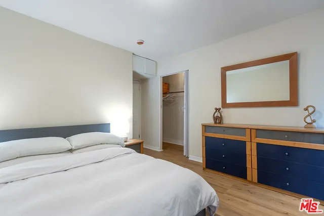 a bedroom with a bed and a potted plant next to a window