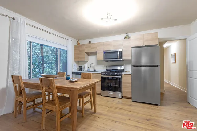 a kitchen with stainless steel appliances granite countertop a stove a refrigerator a kitchen island a table and chairs in it