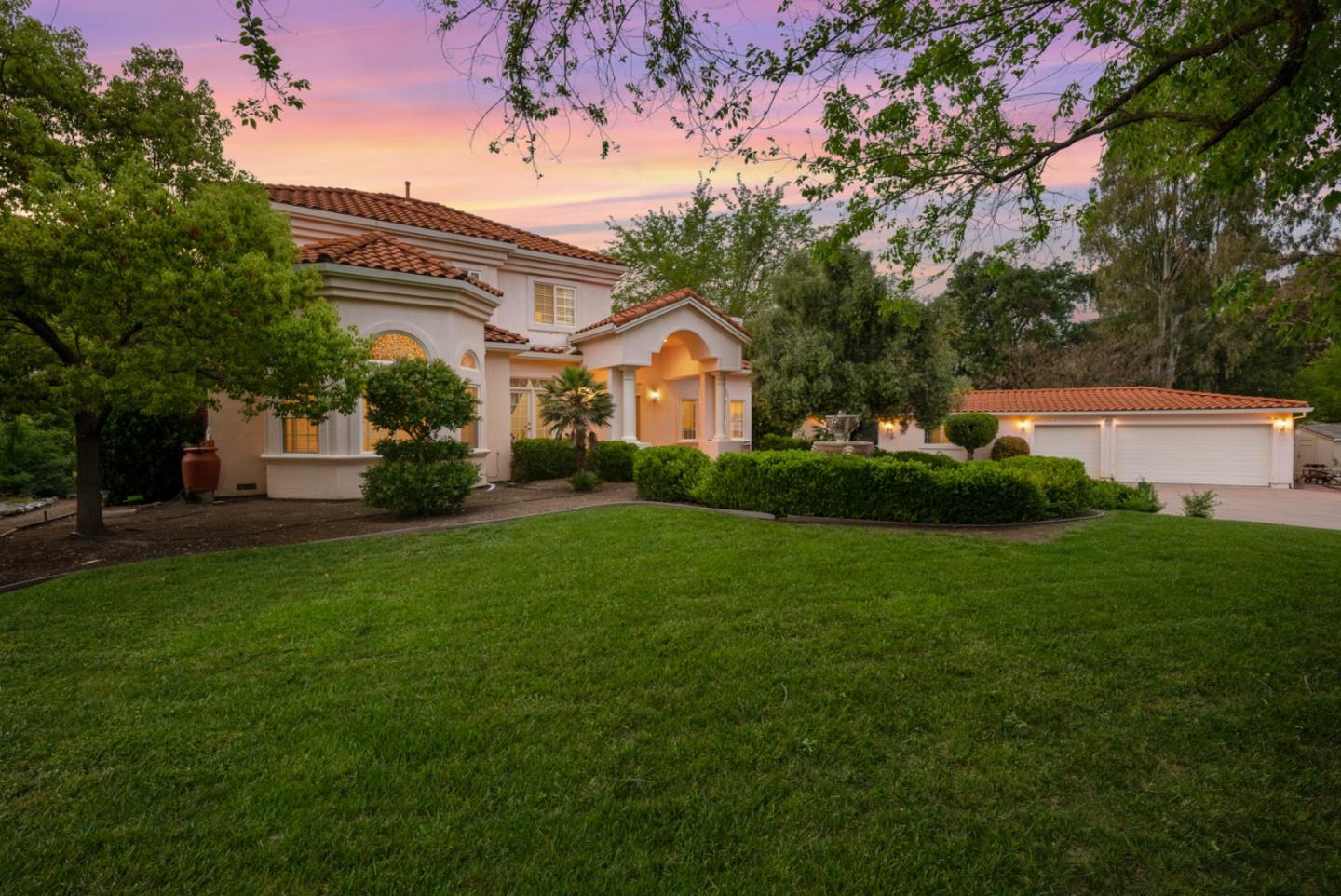 a front view of a house with a garden and trees