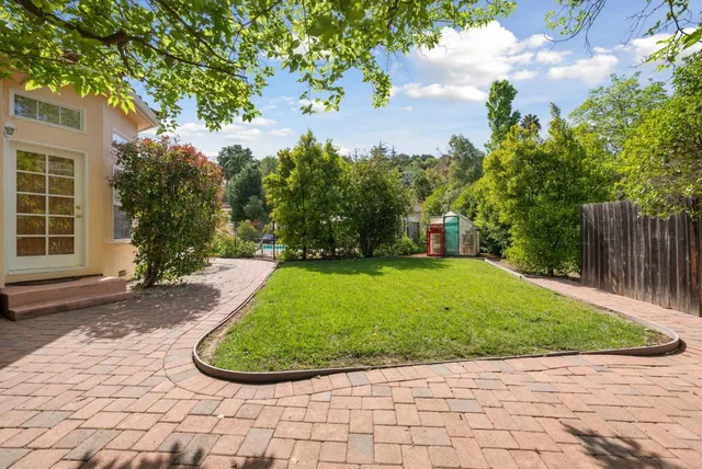 a view of a house with a big yard plants and large tree