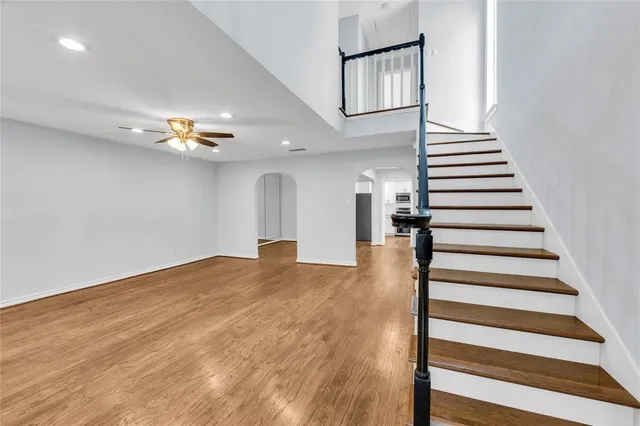 a view of an empty room with chandelier fan and wooden floor