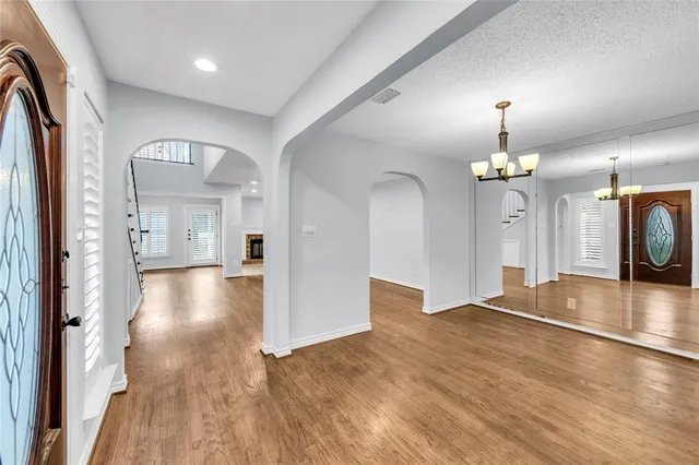 an empty room with wooden floor and kitchen view