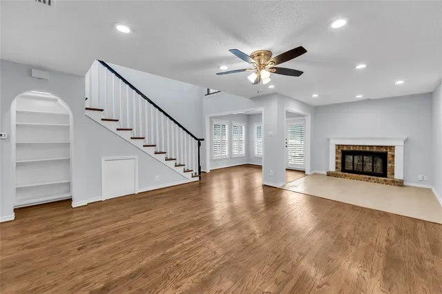 a view of an empty room with stairs wooden floor and windows