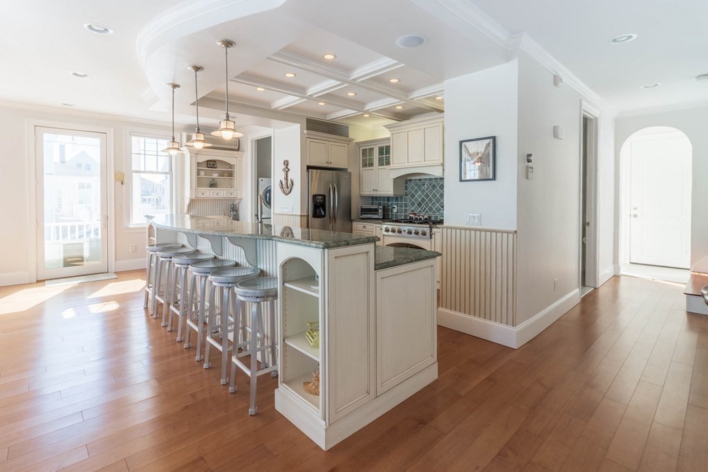 73 K Street Hull, MA 02045 - Photo 14 of 42 a kitchen with stainless steel appliances granite countertop a refrigerator a stove top oven a sink dishwasher and white cabinets with wooden floor