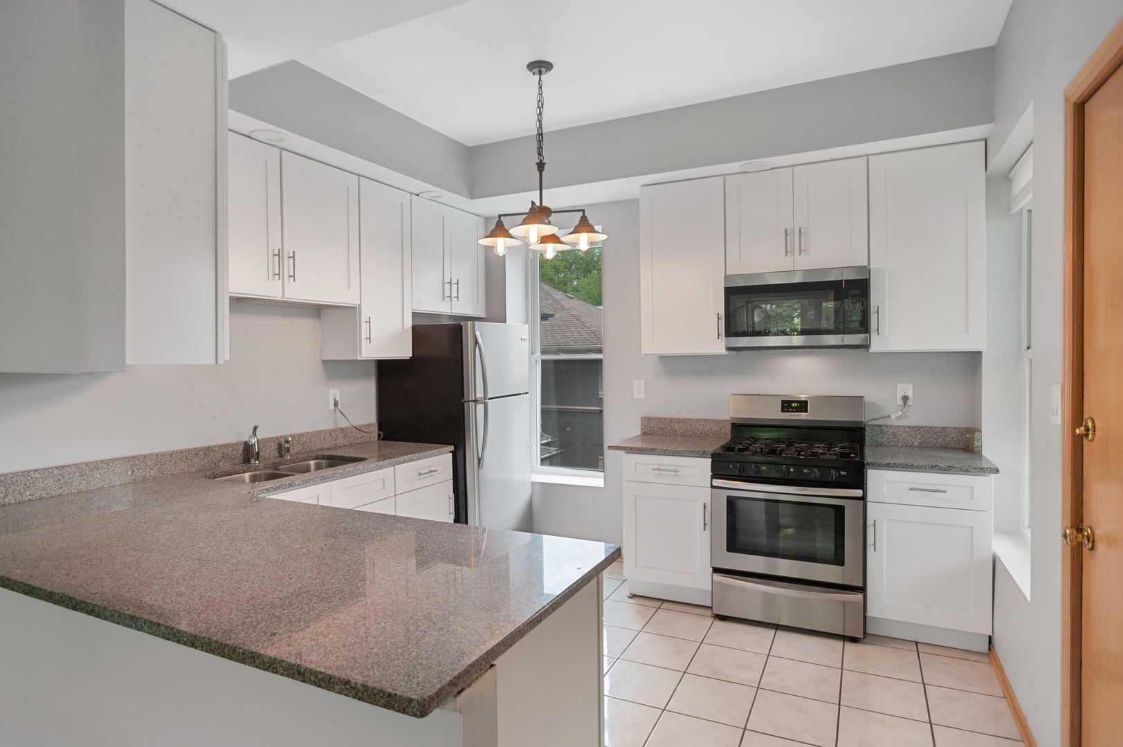 5556 North Wayne Avenue Chicago, IL 60640 - Photo 30 of 37 a kitchen with stainless steel appliances granite countertop a sink a stove a microwave and a refrigerator